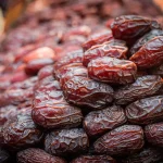 Elinde parlak Medine hurması tutan bir kişi.